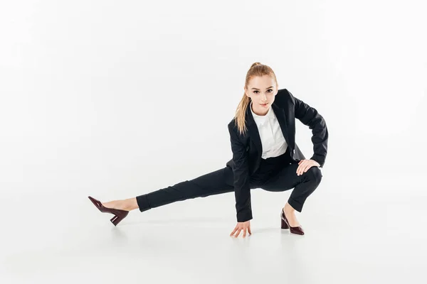 Businesswoman in suit stretching and looking at camera isolated on white — Stock Photo