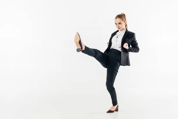 Mujer de negocios realizando karate kick en traje y tacones altos aislados en blanco - foto de stock