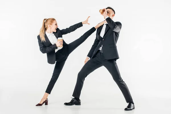 Businesswoman in suit kicking businessman with coffee to go isolated on white — Stock Photo