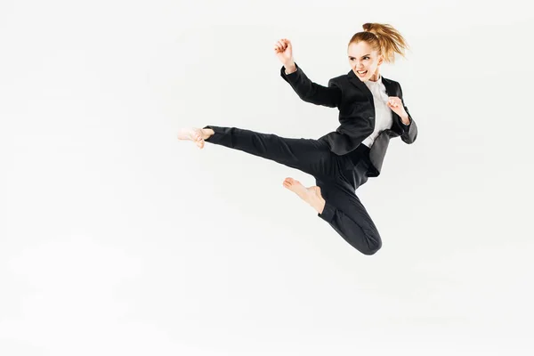 Businesswoman screaming, jumping and performing kick in suit isolated on white — Stock Photo