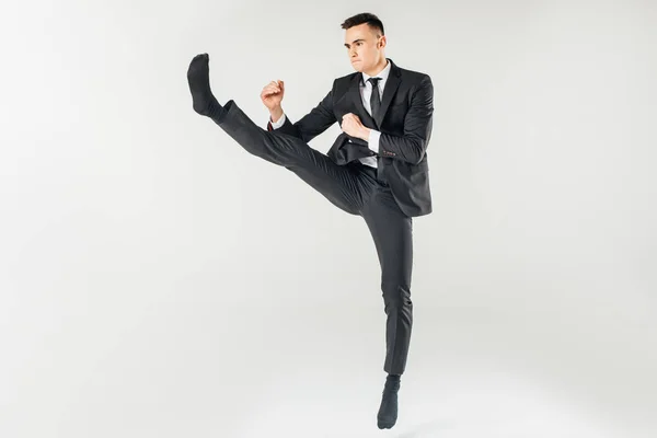 Hombre de negocios saltando y realizando patada en traje aislado en blanco - foto de stock