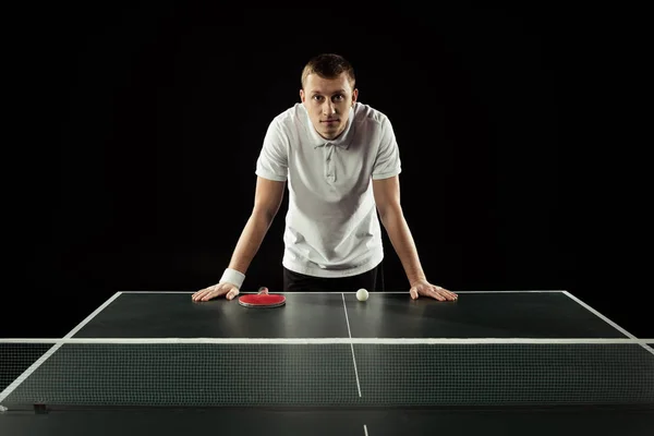 Retrato del jugador de tenis apoyado en la mesa de tenis aislado en negro — Stock Photo