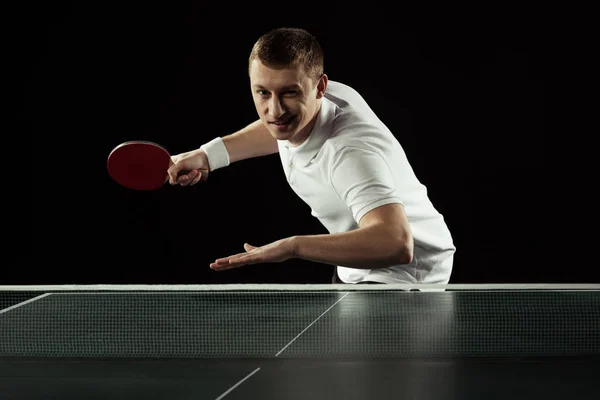 Young tennis player in uniform practicing in table tennis isolated on black — Stock Photo