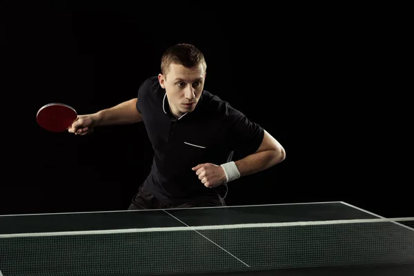 Tennista concentrato che gioca a ping pong isolato sul nero — Foto stock