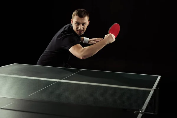 Portrait of emotional tennis player playing table tennis isolated on black — Stock Photo