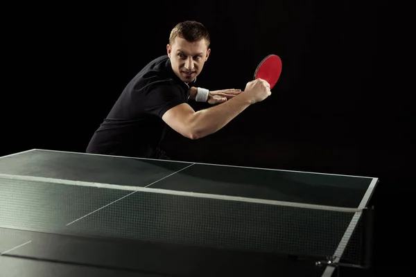 Retrato de jugador de tenis emocional jugando tenis de mesa aislado en negro - foto de stock