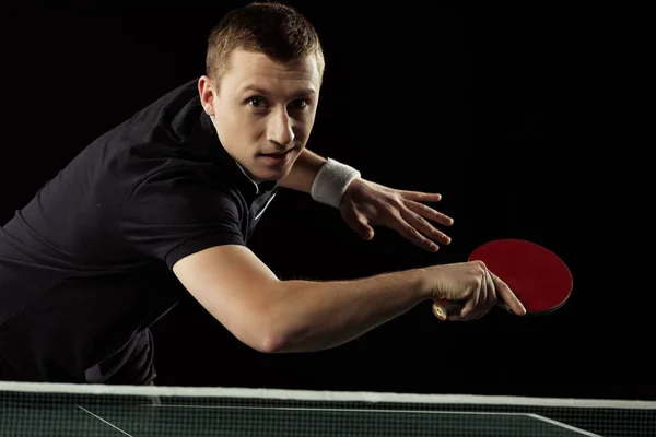 Portrait of focused tennis player playing table tennis isolated on black — Stock Photo