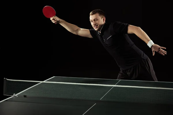 Young tennis player playing table tennis isolated on black — Stock Photo