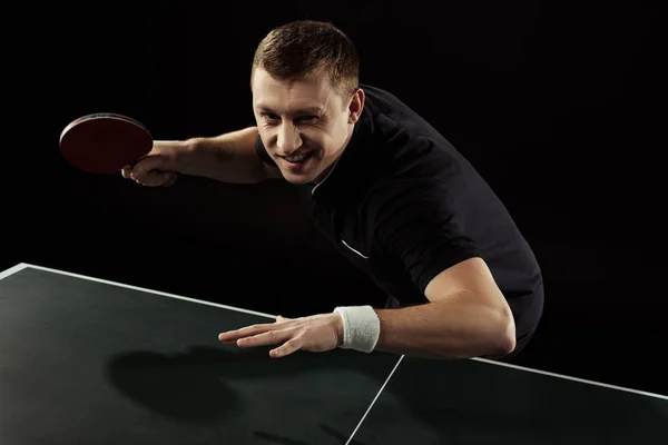 Joueur de tennis émotionnel en uniforme jouant au tennis de table isolé sur noir — Photo de stock