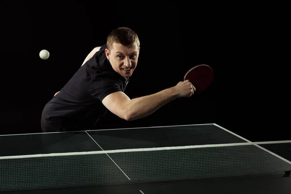 Joueur de tennis émotionnel en uniforme jouant au tennis de table isolé sur noir — Photo de stock