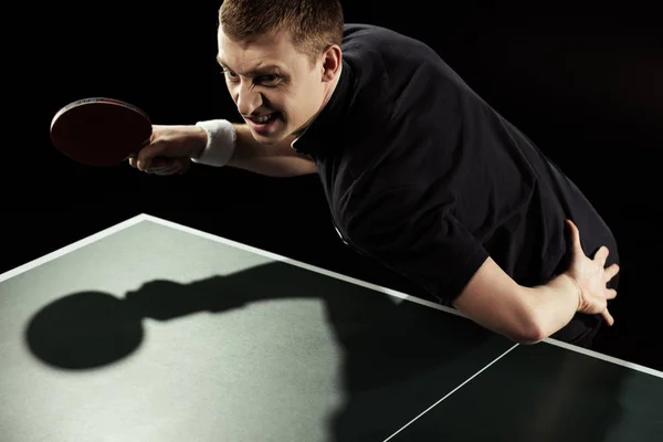 Jogador de tênis zangado em uniforme jogando tênis de mesa isolado em preto — Fotografia de Stock