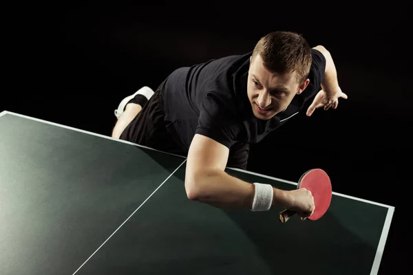 Emotional tennis player in uniform playing table tennis isolated on black — Stock Photo