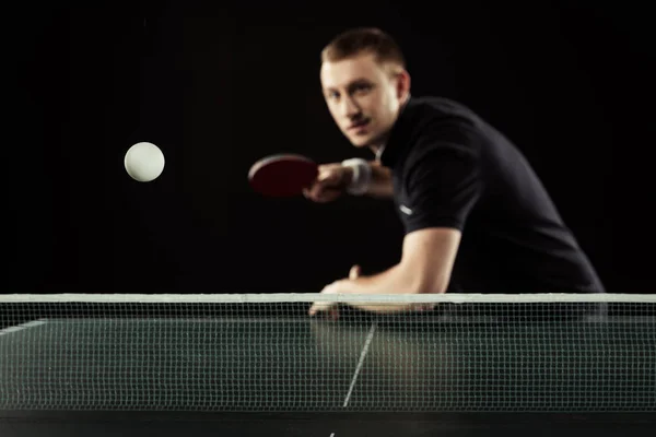 Enfoque selectivo del joven tenista en uniforme jugando al tenis de mesa aislado en negro - foto de stock