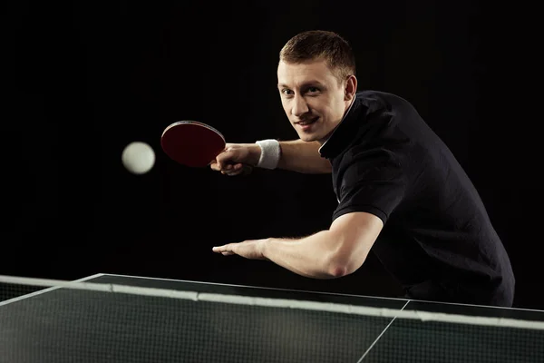 Lächelnder Tennisspieler in Uniform spielt Tischtennis isoliert auf schwarz — Stockfoto