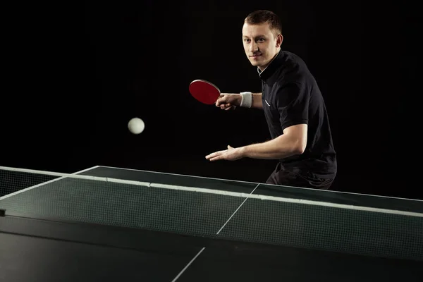 Portrait of tennis player in uniform playing table tennis isolated on black — Stock Photo