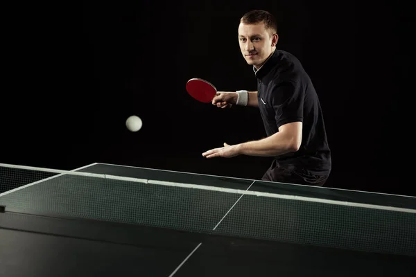 Porträt eines Tennisspielers in Uniform, der Tischtennis isoliert auf schwarz spielt — Stockfoto