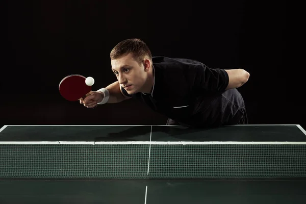 Tennis player in uniform playing table tennis isolated on black — Stock Photo