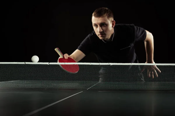 Selective focus of focused tennis player in uniform playing table tennis isolated on black — Stock Photo