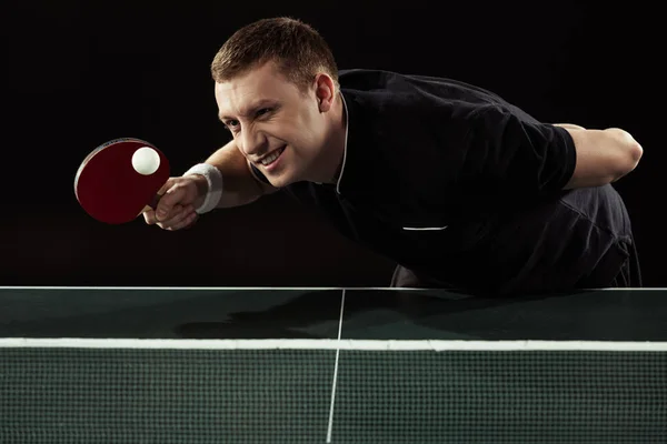 Portrait of emotional tennis player playing table tennis isolated on black — Stock Photo