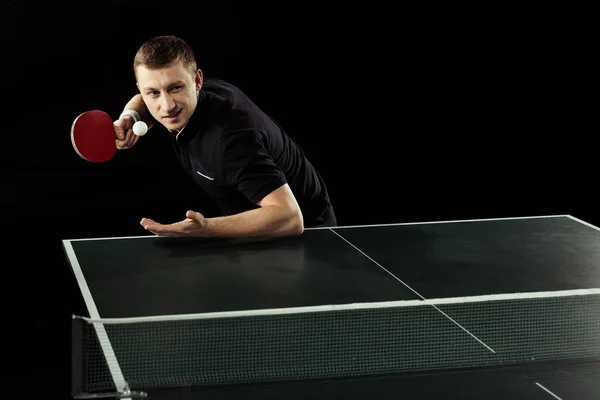 Jugador de tenis enfocado jugando tenis de mesa aislado en negro - foto de stock