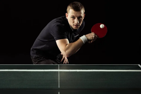 Jugador de tenis enfocado jugando tenis de mesa aislado en negro - foto de stock