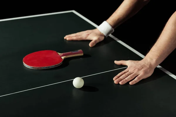 Plan recadré de joueur de tennis appuyé sur une table de tennis avec raquette et balle isolée sur noir — Photo de stock