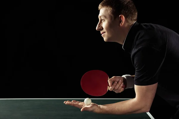 Visão lateral do jogador de tênis sorridente com raquete de tênis e bola em mãos isoladas em preto — Fotografia de Stock
