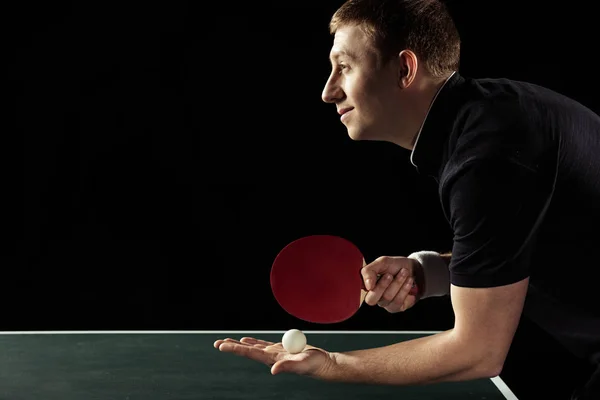 Vue latérale du joueur de tennis souriant avec raquette de tennis et balle dans les mains isolées sur noir — Photo de stock