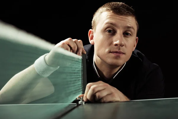 Selective focus of young tennis player looking at camera isolated on black — Stock Photo