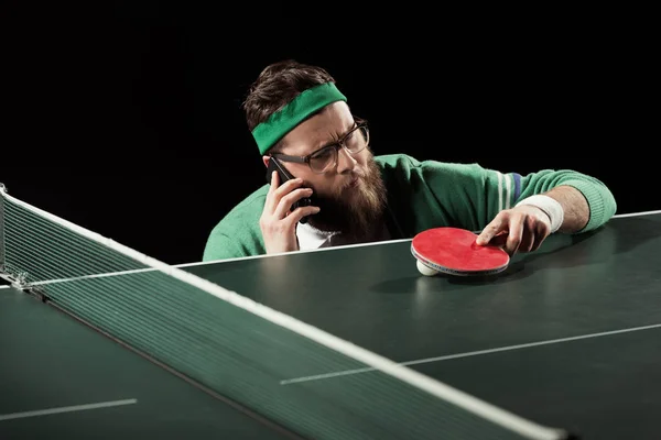 Jogador de tênis falando em smartphone perto de mesa de tênis isolado em preto — Fotografia de Stock