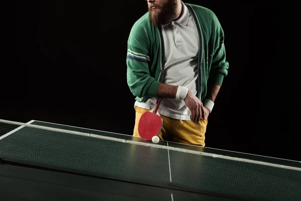 Частичный вид теннисиста с ракеткой, стоящей за теннисным столом, изолированным на черном — стоковое фото