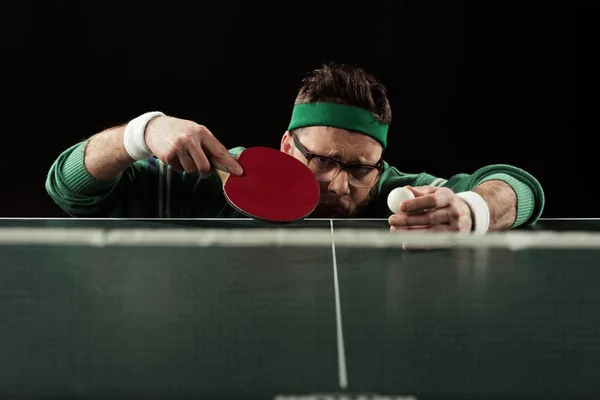 Tennis player with tennis racket and ball at tennis table isolated on black — Stock Photo