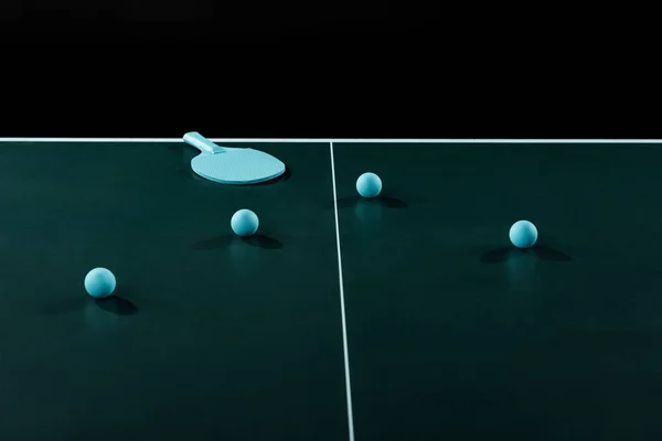 Vista de cerca de raqueta de tenis azul y pelotas en la mesa de tenis aislado en negro - foto de stock