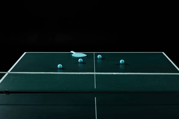 Close up view of blue tennis racket and balls on tennis table isolated on black — Stock Photo