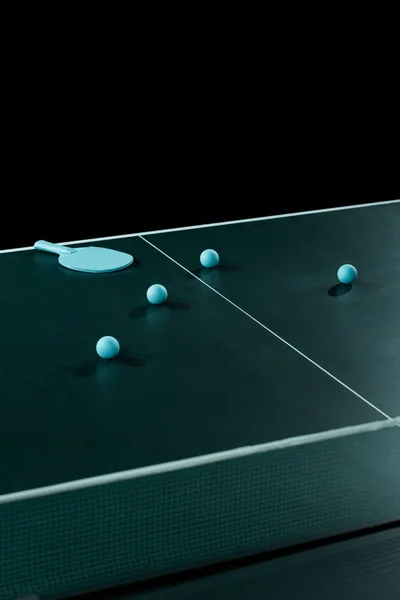 Vista de cerca de raqueta de tenis azul y pelotas en la mesa de tenis aislado en negro - foto de stock