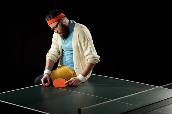 Thoughtful tennis player sitting on tennis table isolated on black — Stock Photo