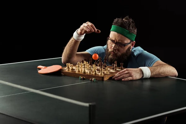 Сфокусированный бородатый теннисист бросает мяч на шахматную доску на теннисном столе — стоковое фото