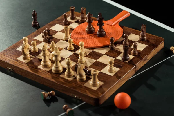 Close up view of tennis racket, ball and chess board with figures on tennis table — Stock Photo