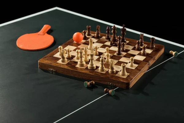 Vista de perto de raquete de tênis, bola e tabuleiro de xadrez com figuras na mesa de tênis — Fotografia de Stock