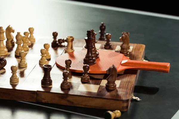 Close up view of tennis racket and chess board with figures on tennis table — Stock Photo