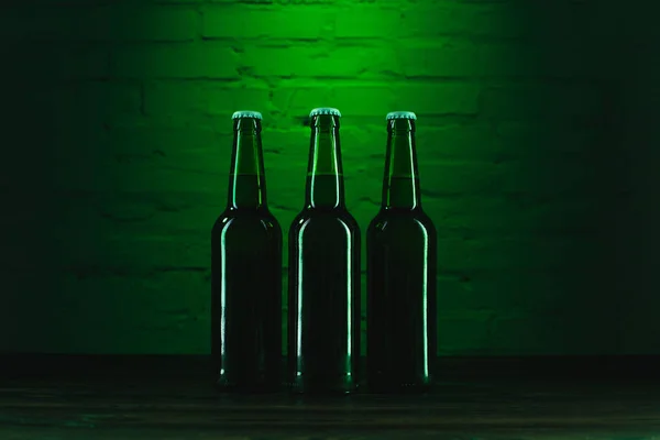 Vista de cerca de botellas verdes de cerveza cerca de la pared de ladrillo verde - foto de stock