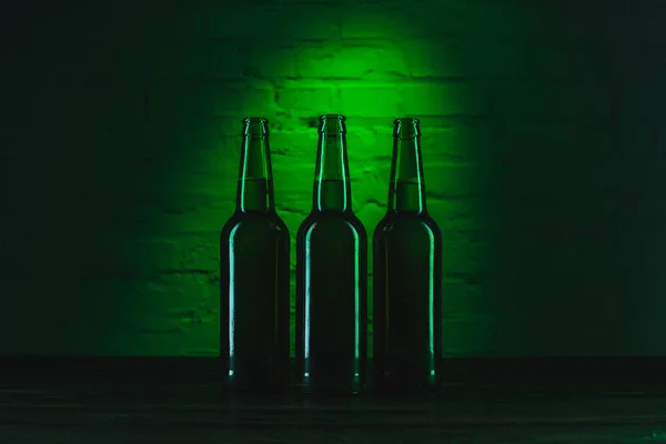 Tre bottiglie di birra verde aperte a luce verde — Foto stock