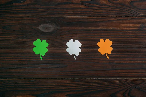 Vue du dessus de trois trèfles aux couleurs du drapeau irlandais sur table en bois — Photo de stock