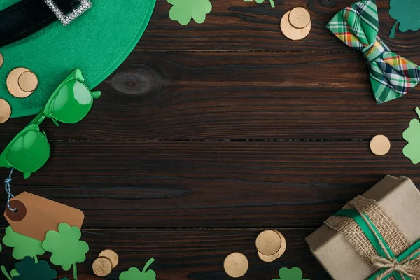 Vue du dessus des pièces d'or, coffret cadeau et accessoires verts sur table en bois — Photo de stock
