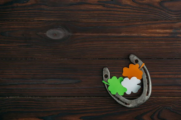Верхний вид подковы и клевера в цветах ирландского флага на деревянном столе — стоковое фото