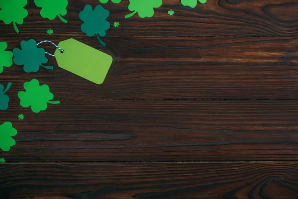 Vue du dessus de l'étiquette verte vierge et des trèfles sur la table en bois — Photo de stock