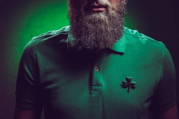 Cropped shot of bearded man wearing green polo shirt with shamrock symbol — Stock Photo