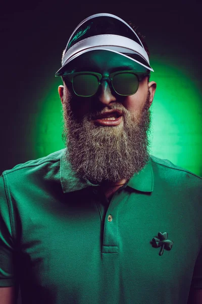 Portrait of bearded young man in green polo shirt with shamrock symbol — Stock Photo