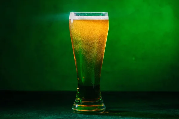 Vista close-up de vidro com cerveja fresca e fria âmbar em verde — Fotografia de Stock