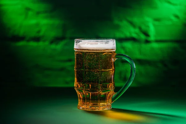 Close-up view of cold beer in glass in green light — Stock Photo